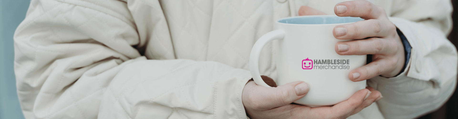 Hands cupping a branded mug showing a company logo